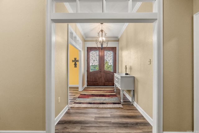 entryway featuring french doors, hardwood / wood-style flooring, an inviting chandelier, and ornamental molding