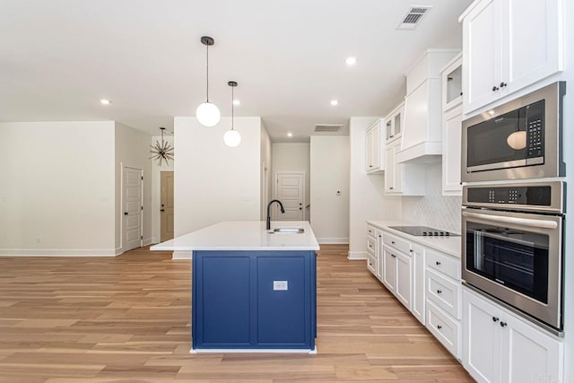 kitchen featuring sink, hanging light fixtures, a center island with sink, white cabinets, and appliances with stainless steel finishes