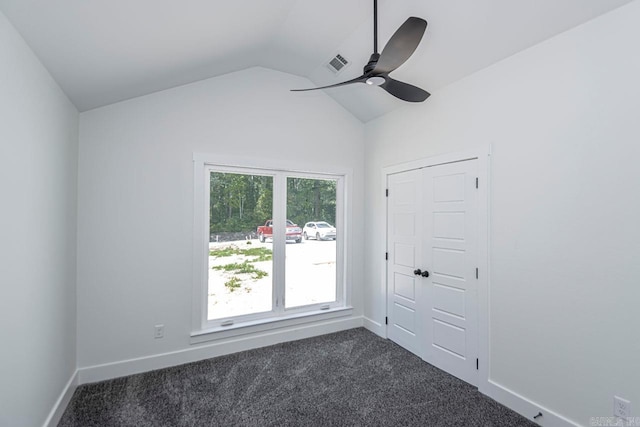 spare room featuring ceiling fan, vaulted ceiling, and dark colored carpet