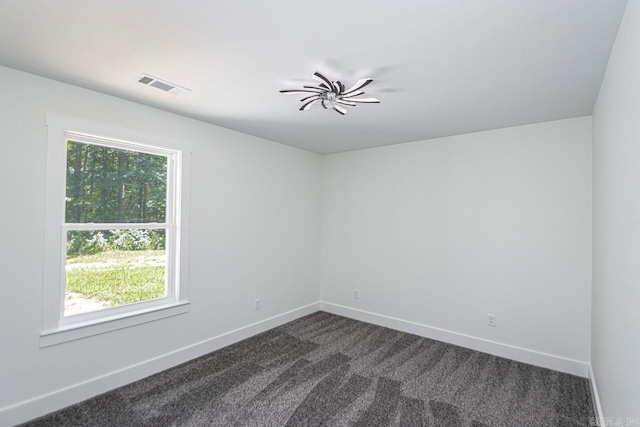 unfurnished room featuring dark carpet and a wealth of natural light