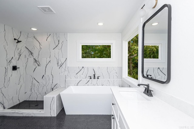 bathroom featuring tile patterned floors, plus walk in shower, vanity, and tile walls