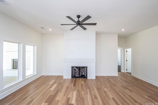 unfurnished living room with ceiling fan, light wood-type flooring, and a fireplace