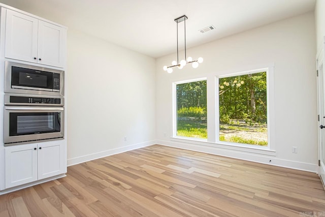 unfurnished dining area with light wood-type flooring and an inviting chandelier