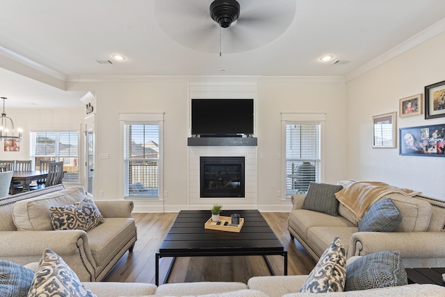 living room with baseboards, a glass covered fireplace, dark wood finished floors, and crown molding