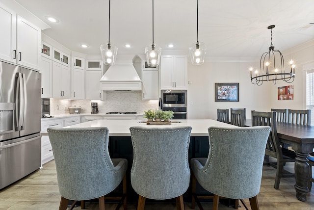 kitchen featuring appliances with stainless steel finishes, a center island, light countertops, and custom exhaust hood