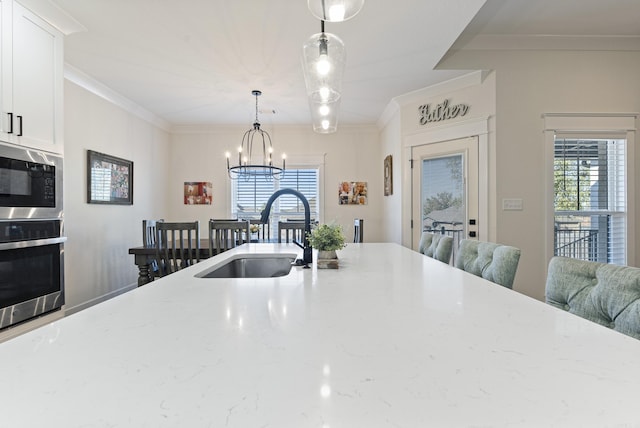 kitchen with crown molding, appliances with stainless steel finishes, a sink, and pendant lighting