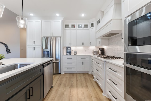 kitchen featuring white cabinets, premium range hood, pendant lighting, and light countertops