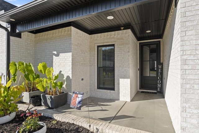 property entrance with a patio and brick siding