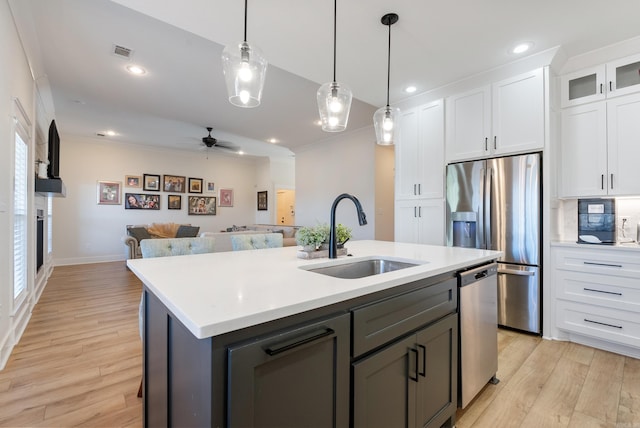 kitchen featuring light countertops, appliances with stainless steel finishes, open floor plan, white cabinetry, and a sink