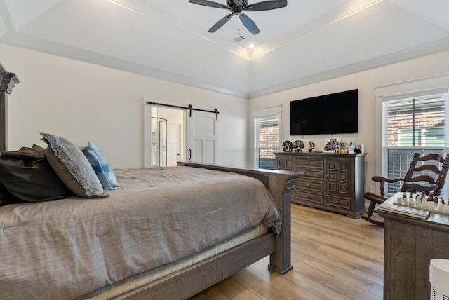 bedroom with ceiling fan, a barn door, multiple windows, and light wood-style flooring