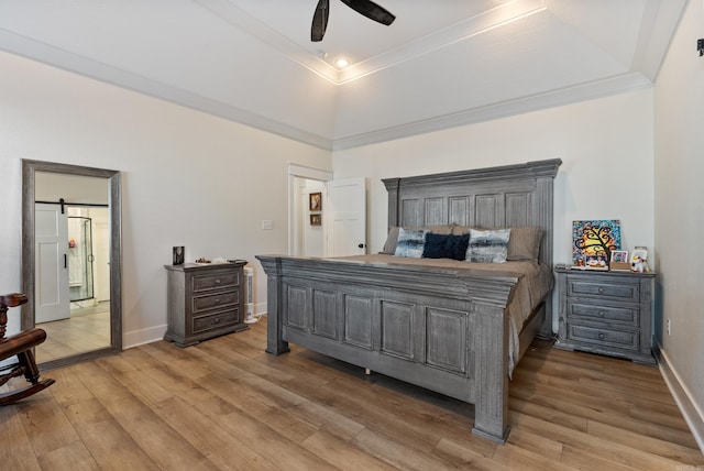 bedroom featuring a barn door, wood finished floors, a ceiling fan, baseboards, and a raised ceiling