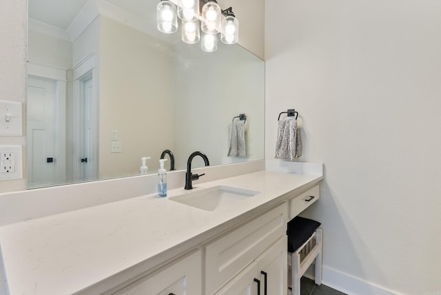 bathroom featuring ornamental molding, an inviting chandelier, vanity, and baseboards