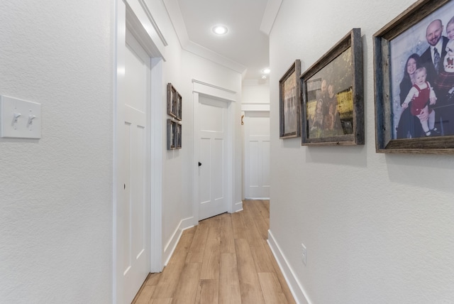 corridor with a textured wall, recessed lighting, light wood-style flooring, and baseboards