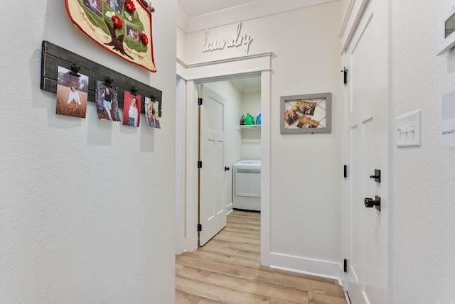 hallway featuring light wood-style floors, baseboards, and washer / clothes dryer