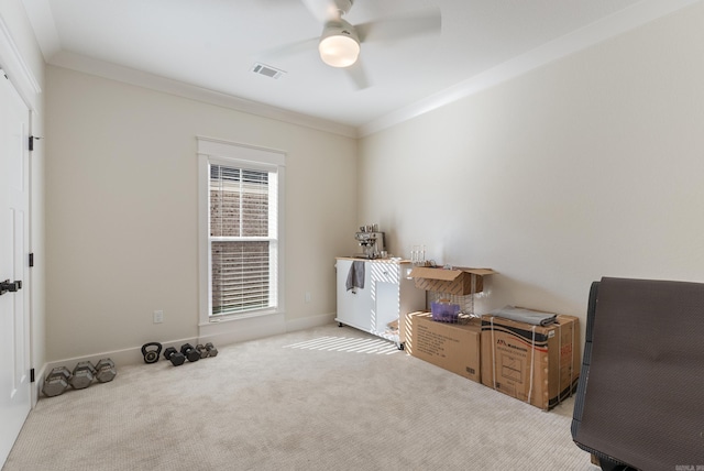 interior space featuring baseboards, visible vents, a ceiling fan, light colored carpet, and ornamental molding