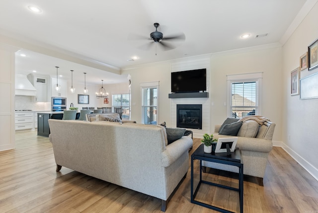 living area with a large fireplace, a healthy amount of sunlight, and light wood-style floors