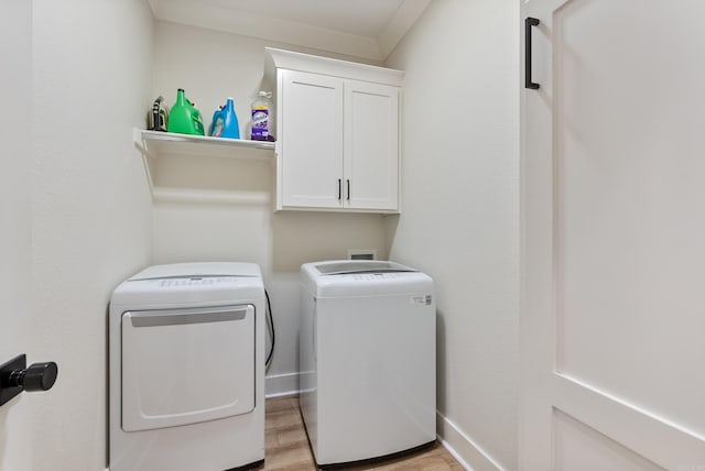 washroom featuring light wood-style flooring, washing machine and clothes dryer, cabinet space, and baseboards