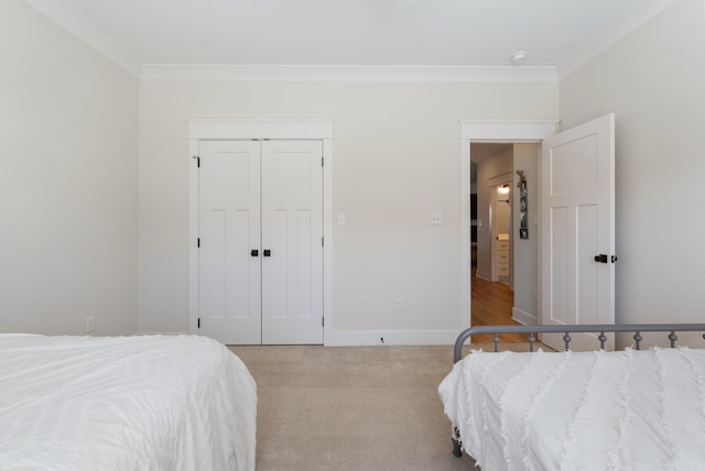 bedroom featuring a closet, light carpet, crown molding, and baseboards