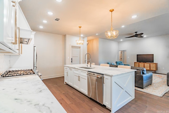 kitchen featuring light stone countertops, sink, stainless steel dishwasher, pendant lighting, and white cabinets