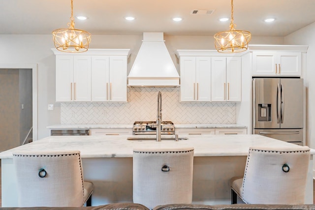 kitchen with stainless steel fridge with ice dispenser, custom range hood, hanging light fixtures, and a chandelier