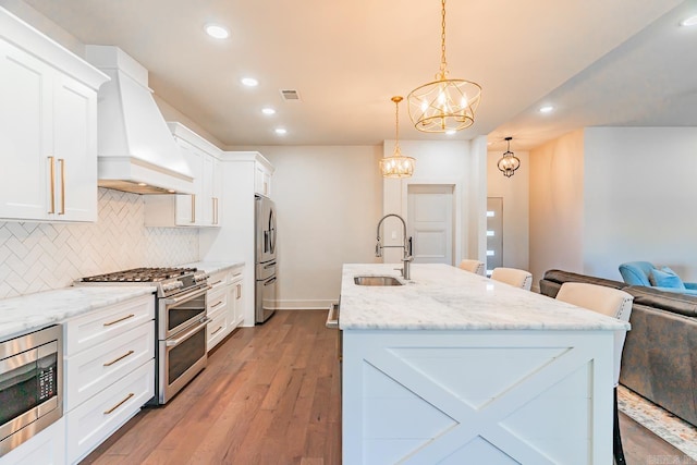 kitchen with a kitchen breakfast bar, pendant lighting, sink, and stainless steel appliances