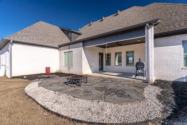 rear view of house featuring ceiling fan, a patio area, and an outdoor fire pit