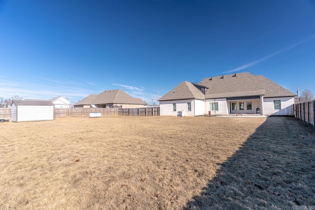 rear view of property featuring a storage unit and a lawn