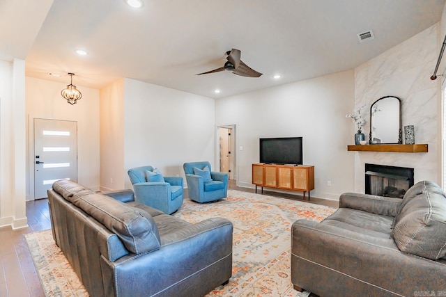 living room featuring a fireplace, light hardwood / wood-style floors, and ceiling fan with notable chandelier