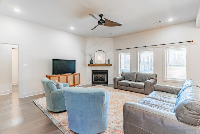 living room with a fireplace, wood-type flooring, and ceiling fan