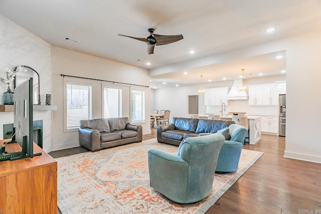 living room featuring hardwood / wood-style flooring, ceiling fan, and sink