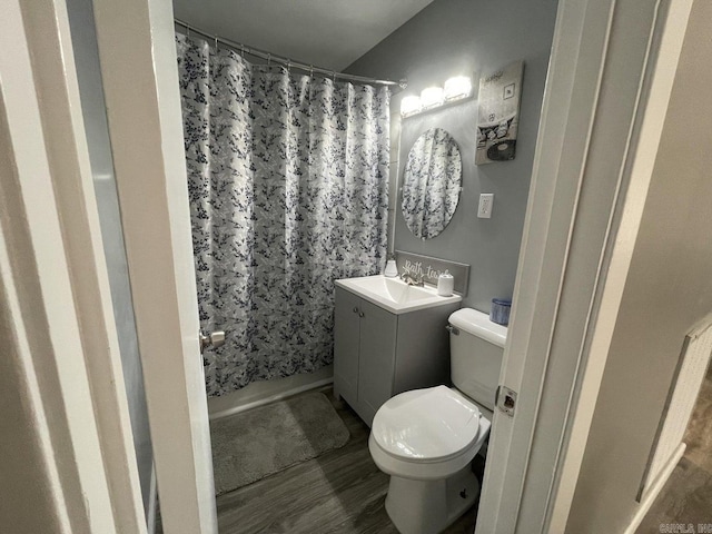 full bathroom with shower / bath combo with shower curtain, hardwood / wood-style floors, vanity, and toilet