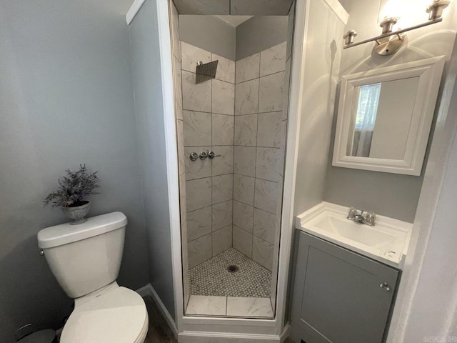 bathroom with a tile shower, vanity, and toilet