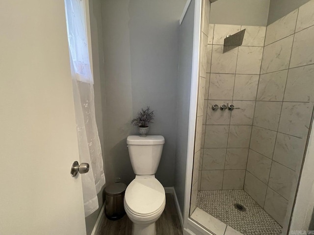 bathroom featuring a tile shower, hardwood / wood-style flooring, and toilet