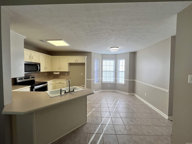 kitchen featuring kitchen peninsula, sink, light tile patterned floors, appliances with stainless steel finishes, and white cabinetry