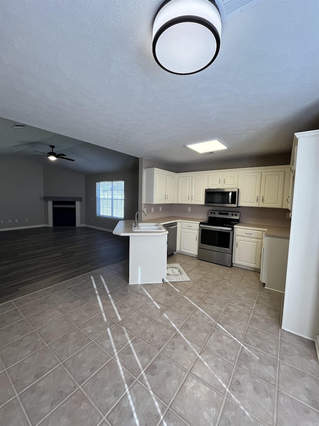 kitchen featuring kitchen peninsula, stainless steel appliances, ceiling fan, sink, and light tile patterned flooring