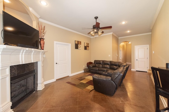 tiled living room featuring ceiling fan, crown molding, and a tiled fireplace