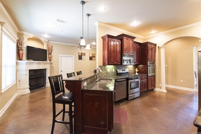 kitchen with pendant lighting, sink, appliances with stainless steel finishes, kitchen peninsula, and a breakfast bar area