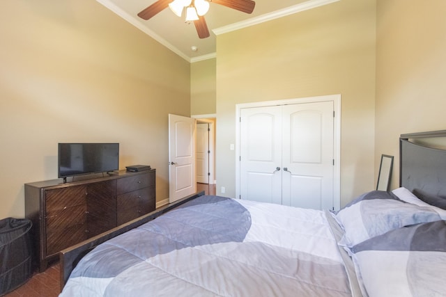 bedroom with ceiling fan, dark wood-type flooring, high vaulted ceiling, crown molding, and a closet