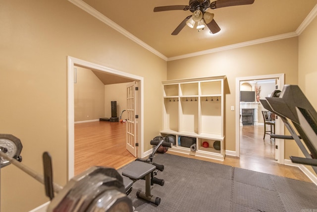 exercise room with hardwood / wood-style flooring, ceiling fan, ornamental molding, and a tiled fireplace