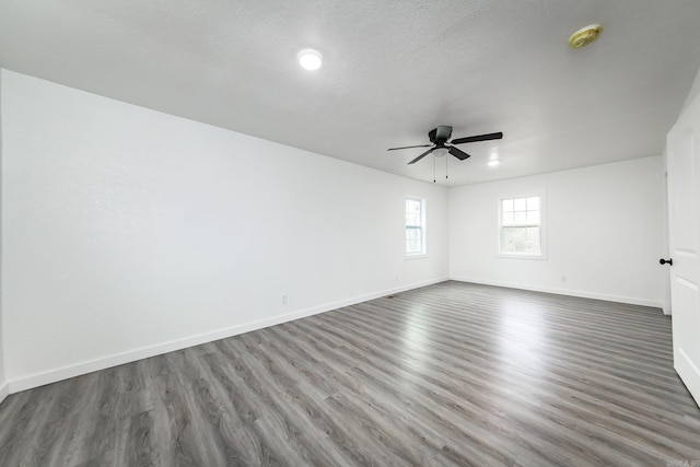 empty room featuring dark hardwood / wood-style floors, ceiling fan, and a textured ceiling