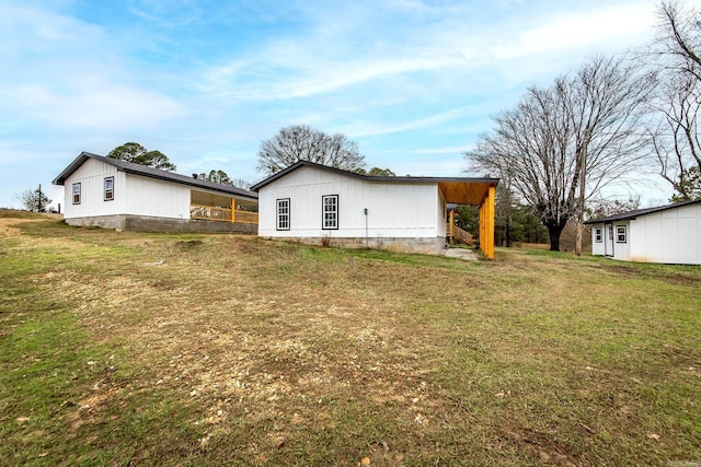 rear view of property featuring an outdoor structure and a lawn