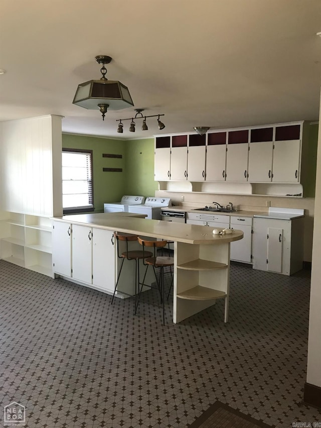 kitchen with dark carpet, independent washer and dryer, white cabinetry, and sink