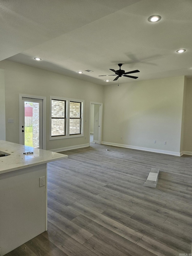 unfurnished living room with dark hardwood / wood-style flooring and ceiling fan