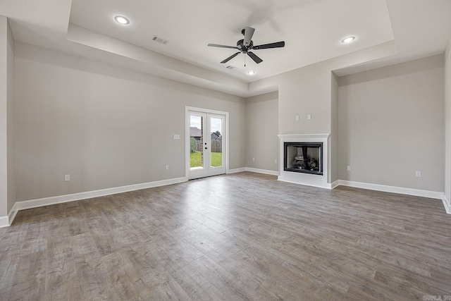 unfurnished living room featuring french doors, a raised ceiling, and ceiling fan