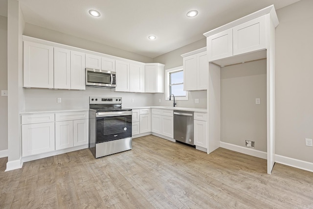 kitchen with white cabinetry, sink, stainless steel appliances, and light hardwood / wood-style floors