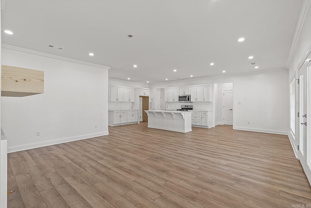 unfurnished living room with light hardwood / wood-style flooring, ornamental molding, and sink