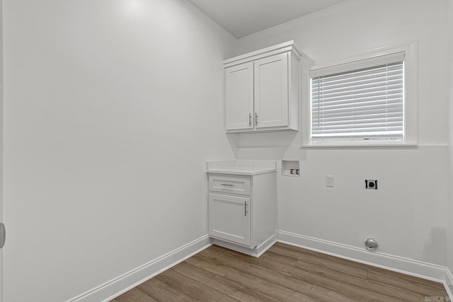 laundry room with hookup for an electric dryer, washer hookup, light hardwood / wood-style floors, and cabinets