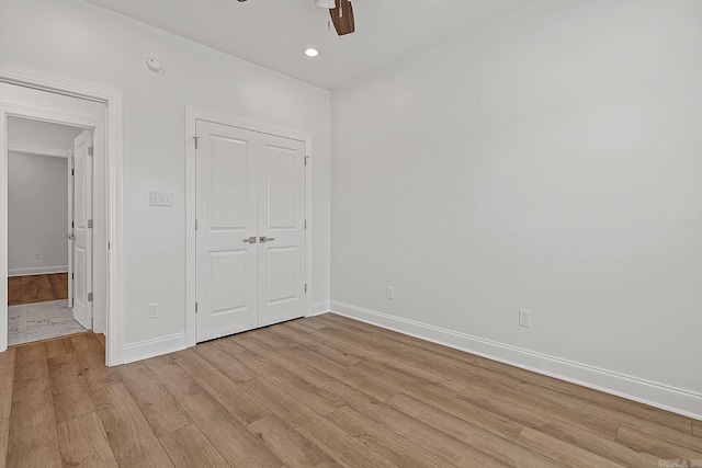 unfurnished bedroom with ceiling fan, light wood-type flooring, and a closet