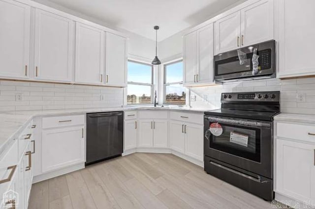 kitchen with white cabinetry, pendant lighting, black appliances, and light hardwood / wood-style floors