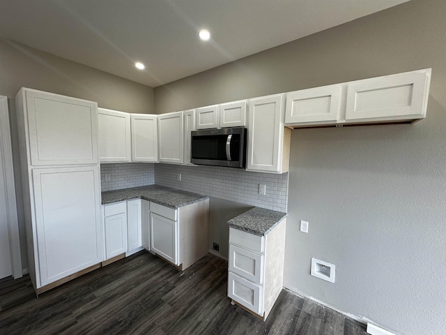 kitchen featuring white cabinetry, dark hardwood / wood-style floors, decorative backsplash, and dark stone countertops